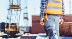 Roofing contractor in Spokane WA inspecting a building site with safety gear and construction tools.